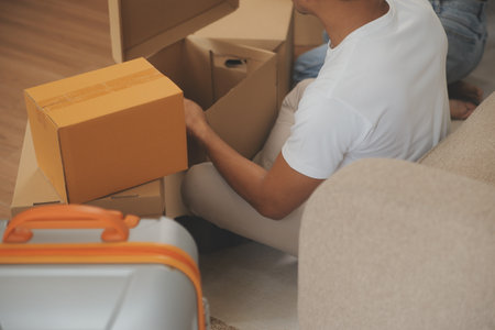 Beautiful young couple in love having fun unpacking things from cardboard boxes while moving in...