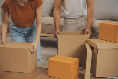 Beautiful young couple in love having fun unpacking things from cardboard boxes while moving in...
