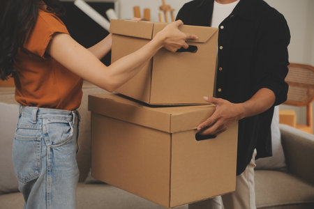 Beautiful young couple in love having fun unpacking things from cardboard boxes while moving in together in their new apartmentの写真素材