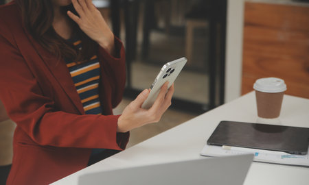 Portrait of a happy Asian businesswoman using mobile phone indoor, Asian businesswoman working in modern office.の写真素材