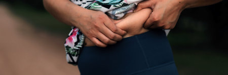 Women body fat belly. Obese woman hand holding excessive belly fat. diet lifestyle concept to reduce belly and shape up healthy stomach muscle.の写真素材