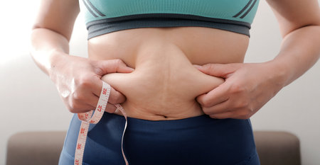 Women body fat belly. Obese woman hand holding excessive belly fat. diet lifestyle concept to reduce belly and shape up healthy stomach muscle.の写真素材