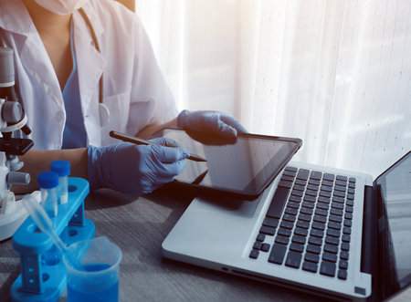 Young scientists conducting research investigations in a medical laboratory, a researcher in the foreground is using a microscopeの写真素材