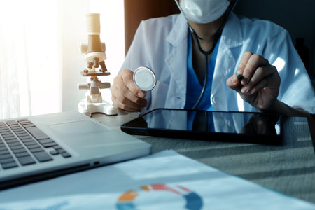 Young scientists conducting research investigations in a medical laboratory, a researcher in the foreground is using a microscopeの写真素材