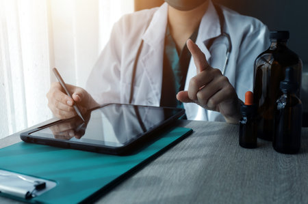 Research and experiments in the pharmaceutical or chemical industry. Female scientist in lab or chemist making notes on laptop by studying liquid in test tube. Scientists working on the background.の写真素材