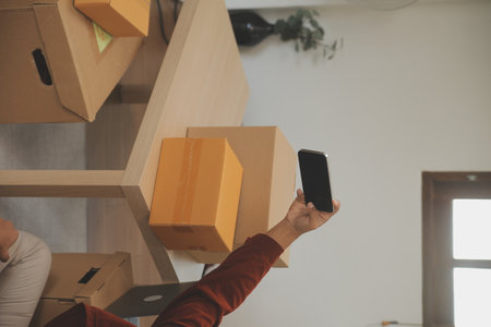 Beautiful young couple in love having fun unpacking things from cardboard boxes while moving in together in their new apartmentの写真素材