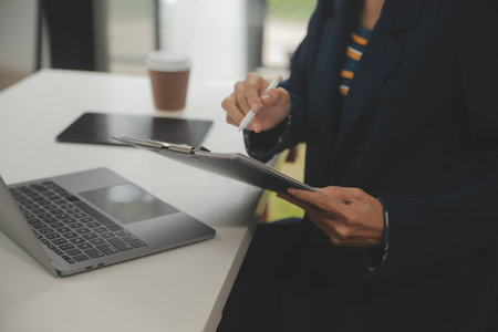 Asian Businesswoman Using laptop computer and working at office with calculator document on desk,...