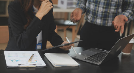 Financial analysts analyze business financial reports on a digital tablet planning investment project during a discussion at a meeting of corporate showing the results of their successful teamwork.の写真素材