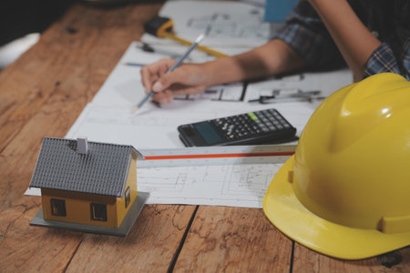 Team of multiethnic architects working on construction plans in meeting room. Engineers discussing on project in office. Mature businessman and woman standing around table working on blueprint.の写真素材