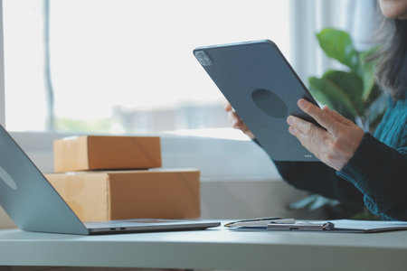 Startup SME small business entrepreneur of freelance Asian woman using a laptop with box Cheerful success Asian woman her hand lifts up online marketing packaging box and delivery SME idea conceptの写真素材