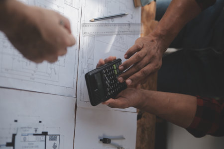 Close up of civil male engineer asian working on blueprint architectural project at construction site at desk in office.の写真素材