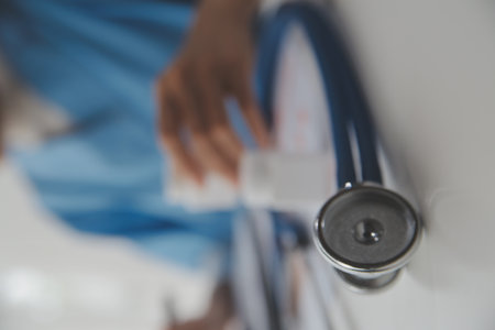 Stethoscope and background doctor using laptop at desk in clinic working on computer at room office.の写真素材