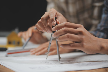 Team of multiethnic architects working on construction plans in meeting room. Engineers discussing on project in office. Mature businessman and woman standing around table working on blueprint.の写真素材