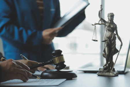 Business and lawyers discussing contract papers with brass scale on desk in office. Law, legal services, advice, justice and law concept picture with film grain effectの写真素材