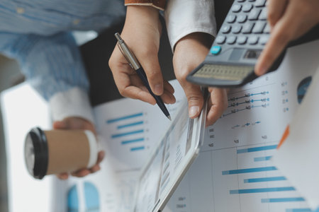Financial analysts analyze business financial reports on a digital tablet planning investment project during a discussion at a meeting of corporate showing the results of their successful teamwork.の写真素材