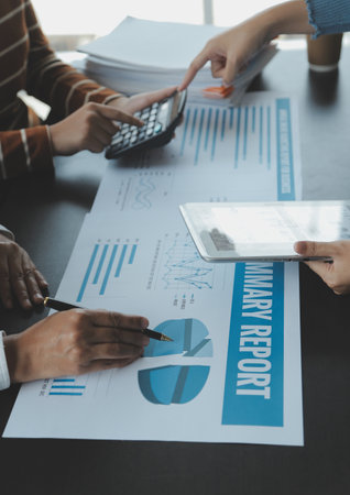 Financial analysts analyze business financial reports on a digital tablet planning investment project during a discussion at a meeting of corporate showing the results of their successful teamwork.の写真素材