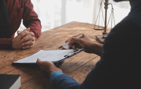 Justice and Law concept. Legal counsel presents to the client a signed contract with gavel and legal law or legal having team meeting at law firm in backgroundの写真素材