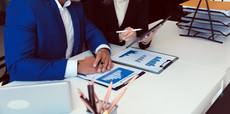 Entrepreneur Asian businessman and businesswoman discussing new business project in tablet in modern...