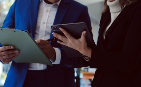 Entrepreneur Asian businessman and businesswoman discussing new business project in tablet in modern Meeting In Modern Office, Asian business casual concept.の写真素材