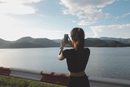 Young woman traveler in casual clothes with backpack from back on background of beautiful view on...