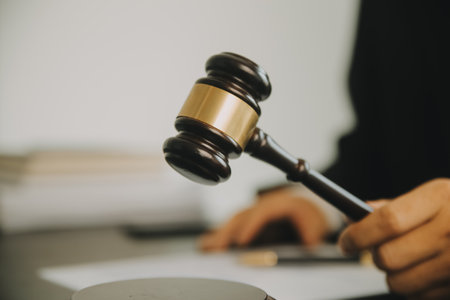 Justice and Law concept. Legal counsel presents to the client a signed contract with gavel and legal law or legal having team meeting at law firm in backgroundの写真素材