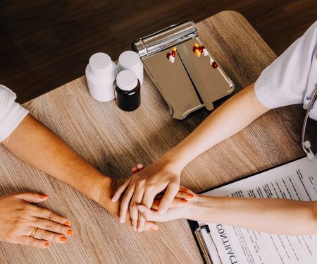 Doctor giving hope. Close up shot of young female physician leaning forward to smiling elderly lady patient holding her hand in palms. Woman caretaker in white coat supporting encouraging old personの写真素材