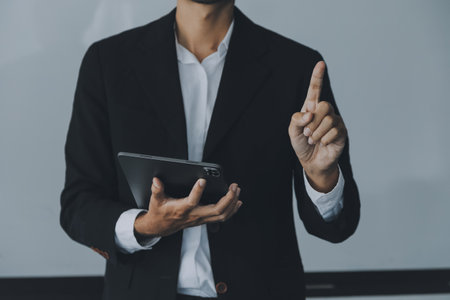 Entrepreneur Asian businessman and businesswoman discussing new business project in tablet in modern Meeting In Modern Office, Asian business casual concept.の写真素材