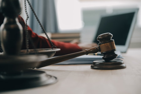 Justice and law concept.Male judge in a courtroom with the gavel, working with, computer and docking keyboard, eyeglasses, on table in morning lightの写真素材