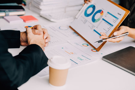 Financial analysts analyze business financial reports on a digital tablet planning investment project during a discussion at a meeting of corporate showing the results of their successful teamwork.の写真素材