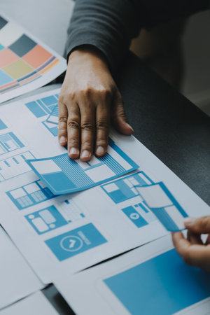 Close up ux developer and ui designer brainstorming about mobile app interface wireframe design on table with customer breif and color code at modern office.Creative digital development agencyの写真素材