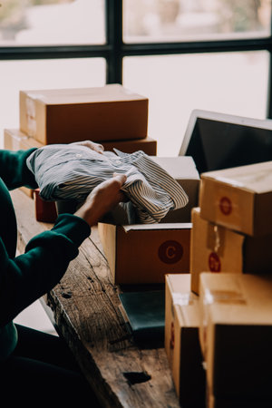 Startup small business entrepreneur or freelance Asian woman using a laptop with box, Young success Asian woman with her hand lift up, online marketing packaging box and delivery, SME concept.の写真素材