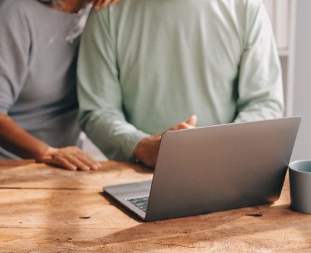 Embraced mature couple surfing the Internet on laptop at homeの写真素材