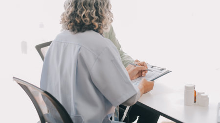 Doctor giving hope. Close up shot of young female physician leaning forward to smiling elderly lady patient holding her hand in palms. Woman caretaker in white coat supporting encouraging old personの写真素材