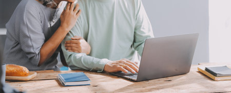 Happy mature couple using laptop at homeの写真素材