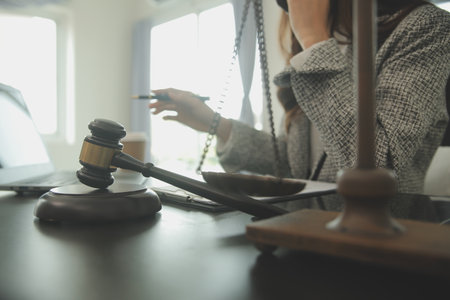 Business and lawyers discussing contract papers with brass scale on desk in office. Law, legal services, advice, justice and law concept picture with film grain effectの写真素材