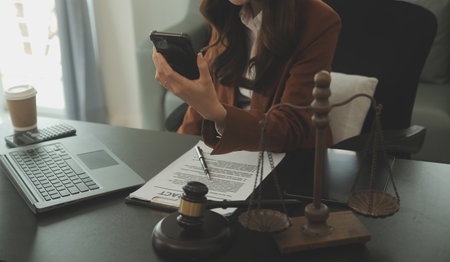 Business and lawyers discussing contract papers with brass scale on desk in office. Law, legal services, advice, justice and law concept picture with film grain effectの写真素材