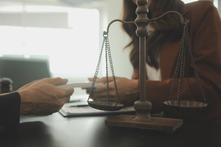 Business and lawyers discussing contract papers with brass scale on desk in office. Law, legal services, advice, justice and law concept picture with film grain effectの写真素材
