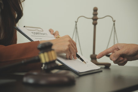 Business and lawyers discussing contract papers with brass scale on desk in office. Law, legal services, advice, justice and law concept picture with film grain effectの写真素材