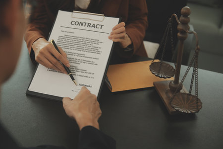 Business and lawyers discussing contract papers with brass scale on desk in office. Law, legal services, advice, justice and law concept picture with film grain effectの写真素材