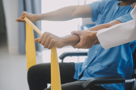 Physiotherapist man giving exercise with dumbbell treatment About Arm and Shoulder of athlete male patient Physical therapy conceptの写真素材