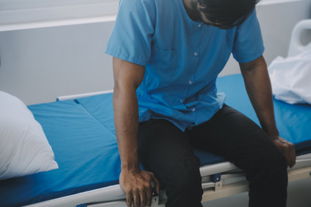 Hospitalized patient lying in a hospital bed at night, a doctor is taking care of her, hand close upの写真素材