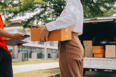 Asian Woman Receiving Product from delivery man at Home, Young Owner Woman Order Product from Smartphone Application, Woman with Online Business or SME Concept.の写真素材