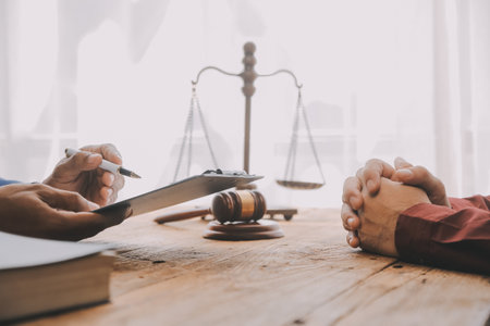 Justice and Law concept. Legal counsel presents to the client a signed contract with gavel and legal law or legal having team meeting at law firm in backgroundの写真素材