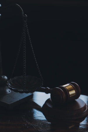 Justice and law concept.Male judge in a courtroom with the gavel, working with, computer and docking keyboard, eyeglasses, on table in morning lightの写真素材