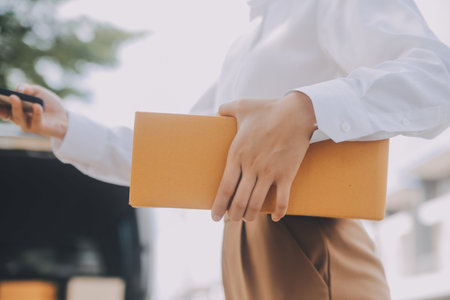 Asian Woman Receiving Product from delivery man at Home, Young Owner Woman Order Product from Smartphone Application, Woman with Online Business or SME Concept.の写真素材