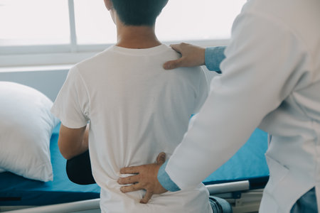 Doctor or physical therapist examines back pain and spinal area to give advice within the rehabilitation center.の写真素材
