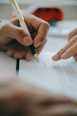 Closeup asian male people car salesman or sales manager offers to sell a car and explains and reads the terms of signing a car contract and insurance.の写真素材