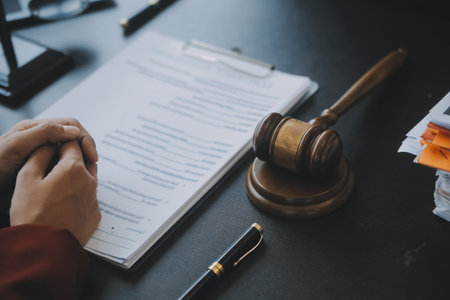 Justice and law concept.Male judge in a courtroom with the gavel, working with, computer and docking keyboard, eyeglasses, on table in morning lightの写真素材