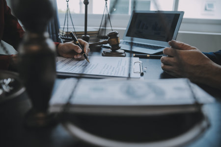 Justice and law concept.Male judge in a courtroom with the gavel, working with, computer and docking keyboard, eyeglasses, on table in morning lightの写真素材