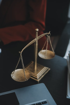 Justice and law concept.Male judge in a courtroom with the gavel, working with, computer and docking keyboard, eyeglasses, on table in morning lightの写真素材
